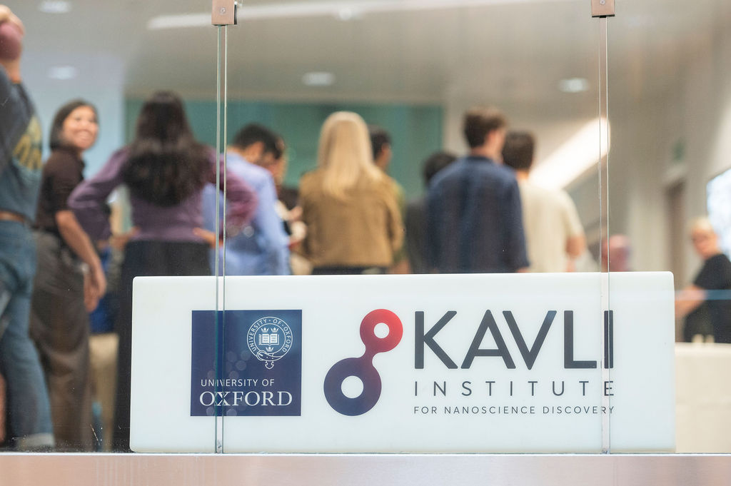 Lightbox showing the Kavli Institute for Nanoscience Discovery and University of Oxford logos in the foreground, symposium delegates in the background