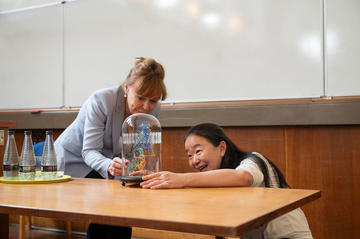 Professor Jue Chen and Professor Carol Robinson both smiling, looking at the glass-blown sculpture commemorating the Oxford Lecture Award 2026